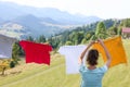 Woman hanging clean laundry with clothespins on washing line in mountains, back view