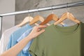 Woman hanging clean T-shirts on rack indoors, closeup