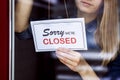 Woman hanging closed sign on small local business shop door window Royalty Free Stock Photo