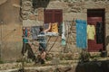 Woman hanging clothes to dry in front of old house