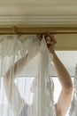 Woman hanging curtains on windows. Woman hanging curtains on windows. Housekeeper hangs curtains