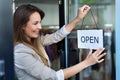 Woman hanging open sign on door