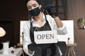 Woman hanging Open sign onto glass door in salon, focus on hands. Beauty services during Coronavirus quarantine