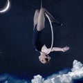 Woman hanging upside-down on aerial hoop at night