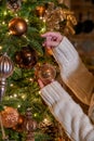 Woman hangs glass bauble on Christmas tree