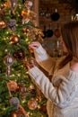 Woman hangs glass bauble on Christmas tree