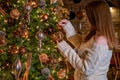 Woman hangs glass bauble on Christmas tree