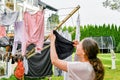 A woman hangs washed wet clothes after washing on a dryer in the yard Royalty Free Stock Photo