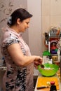 A woman happily prepares a salad in her kitchen. Healthy eating
