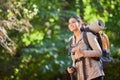 Woman, happy hiking and nature with backpack, trees or binocular in sunshine on forest journey. Hiker girl, smile and