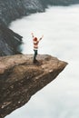 Woman happy raised hands on Trolltunga rocky cliff