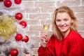 Woman happy smiling near christmas tree enjoy celebration. Girl in red dress relaxing with glass of champagne near Royalty Free Stock Photo