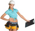 Woman in hard hat and tool belt holding clipboard Royalty Free Stock Photo