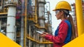 woman in hard hat using tablet at industrial site, analyzing data Royalty Free Stock Photo