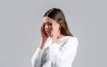 Woman with hard headache holding hands on head. Brunette woman touching her temples feeling stress, on gray background