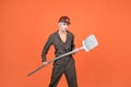 woman hard worker in protective helmet and boilersuit hold shovel on orange background, labour day Royalty Free Stock Photo