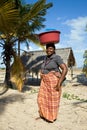 Woman has different goods in a bowl and carries it on her head traditionally.