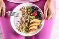 A woman has a healthy breakfast after morning exercise. Yogurt, blackberry muesli, raspberries, blueberries, kiwi and peaches in a Royalty Free Stock Photo