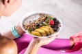 A woman has a healthy breakfast after morning exercise. Yogurt, blackberry muesli, raspberries, blueberries, kiwi and peaches in a