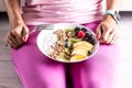 A woman has a healthy breakfast after morning exercise. Yogurt, blackberry muesli, raspberries, blueberries, kiwi and peaches in a