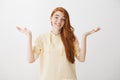 Woman has no idea, nothing to tell. Shrugging unaware attractive female with ginger hair, standing with spread palms and
