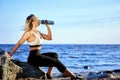 Woman has rest and drinks water during training near seaside. Royalty Free Stock Photo