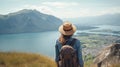 Woman with a hat and backpack looking at the mountains and lake from the top of a mountain in the sunlight, with a view of the Royalty Free Stock Photo