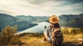Woman with a hat and backpack looking at the mountains and lake from the top of a mountain in the sunlight, with a view of the Royalty Free Stock Photo