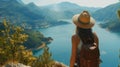 woman with a hat and backpack looking at the mountains and lake from the top of a mountain Royalty Free Stock Photo
