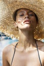 Woman in hat and black stylish swimsuit poses near