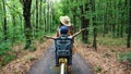 a woman in a hat and dress, with a basket of flowers, together with small child, ride bicycle, in the forest, in the Royalty Free Stock Photo