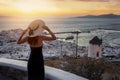 A woman with hat enjoys the beautiful sunset view to the town of Mykonos island Royalty Free Stock Photo