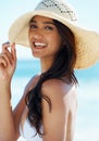Woman, hat and happy at beach in portrait, nature and traveling to ocean for peace on vacation. Female person, outdoors
