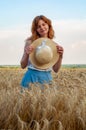 Woman with hat in her hands in summer field golden wheat, beautiful happy girl with golden brown hair, enjoying life. Royalty Free Stock Photo