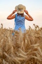 Woman with hat in her hands in summer field golden wheat, beautiful happy girl with golden brown hair, enjoying life. Royalty Free Stock Photo