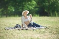 A woman in a hat is holding a glass of red wine in her hand at a picnic. Lady sitting on the grass with a blanket Royalty Free Stock Photo