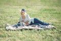 A woman in a hat is holding a glass of red wine in her hand at a picnic. Lady sitting on the grass with a blanket Royalty Free Stock Photo