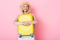 Woman in hat hugging yellow luggage