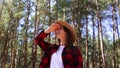 Woman in a hat looks around while walking into the forest. Concept hike, tourism.