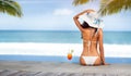 Woman in hat near the sea on beach with tropical cocktail