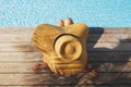 Woman in hat relaxing on wooden pier under palm leaves shadow at pool, enjoying summer vacation Royalty Free Stock Photo