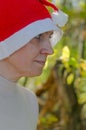 A woman in a hat of Santaclaus with a sly evil face among the autumn foliage as a harbinger of the coming winter.
