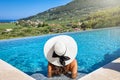 A woman with hat sits in the swimming pool and enjoys the view over Zakynthos island Royalty Free Stock Photo