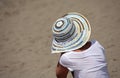 Woman in hat sitting on the beach on sand