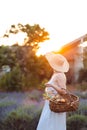 Woman in Hat, Sundress and Basket in her Hands Looks Towards Orange Sun. Lavender Meadow Royalty Free Stock Photo