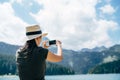 Woman in a hat is taking pictures of the mountains on her phone. Back view Royalty Free Stock Photo