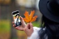 woman in hat taking selfie with smartphone with autumn leaves in the park