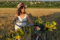 A woman in a hat and a white dress with a bicycle Royalty Free Stock Photo