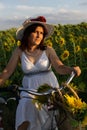 A woman in a hat and a white dress with a bicycle Royalty Free Stock Photo