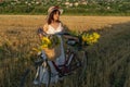 A woman in a hat and a white dress with a bicycle Royalty Free Stock Photo